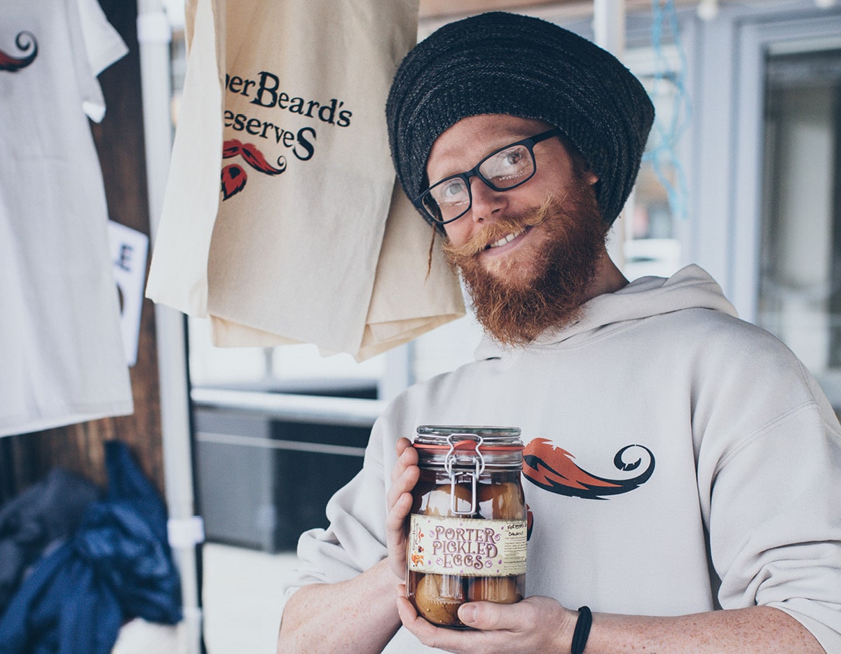 Man from Ginger Beard Pickles and Preserves holding a jar of pickle