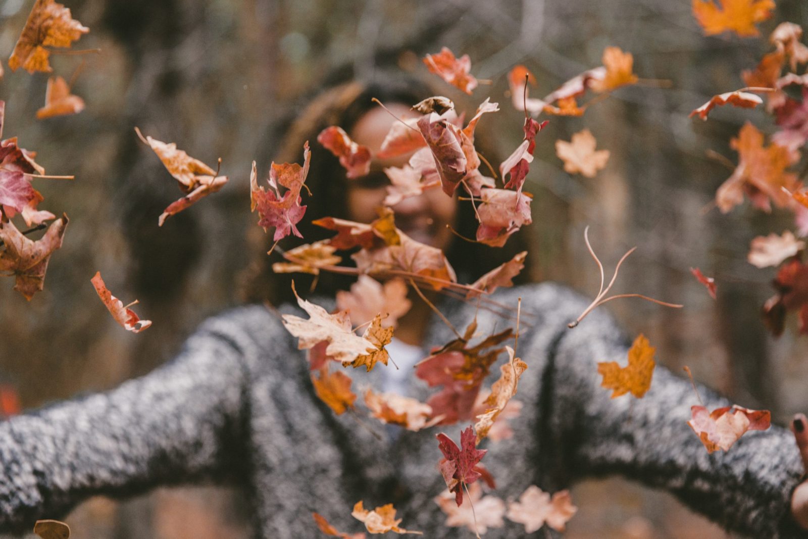 Woman enjoying falling autumn leaves