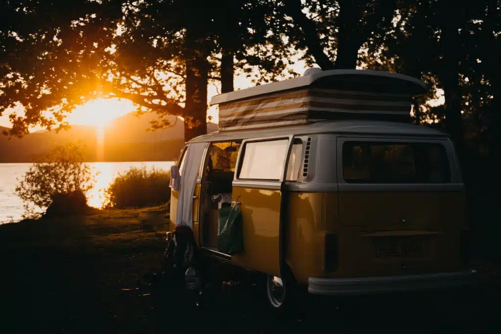 Old fashioned VW camper at a lake at sunset