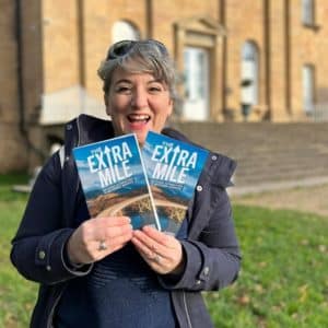 Ele holding The Extra Mile book