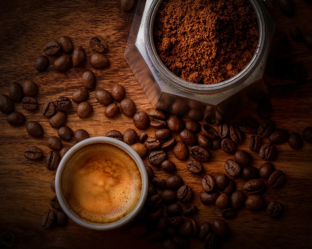 Creamy coffee with beans and coffee grounds around